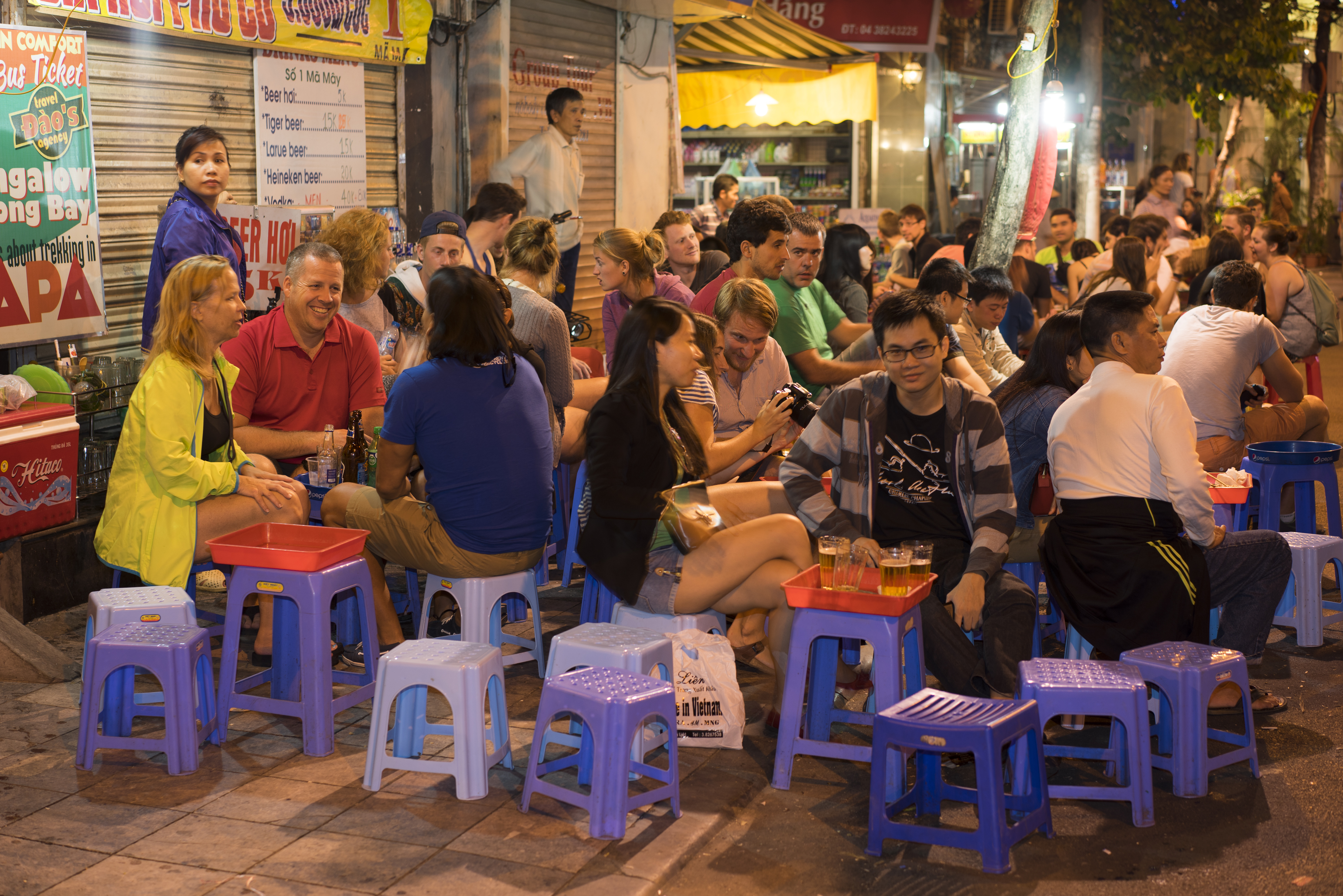 People drink beer on street at night in Hanoi old quarter
