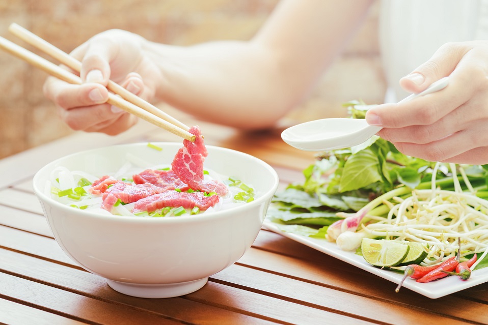 A tourist enjoying the Pho Bo (Noodle with beef) in street cafe of Vietnam.