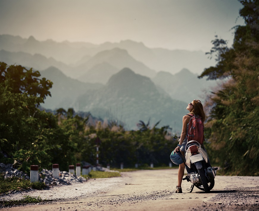 A biker standing near motorbike and enjoying landscape view