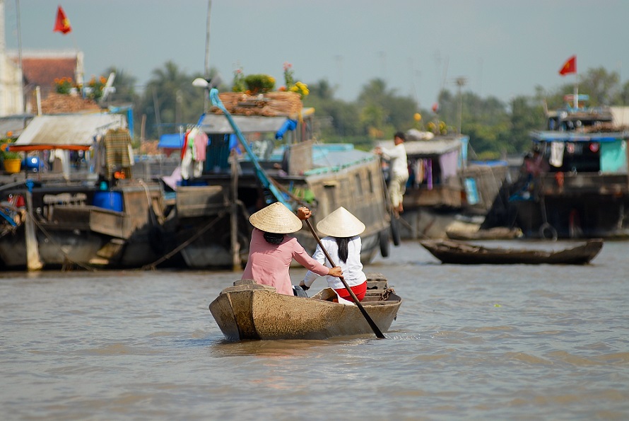 Women cross Mekong river by paddleboat at the famous floating market in Cai Be, Tien Giang province, Vietnam