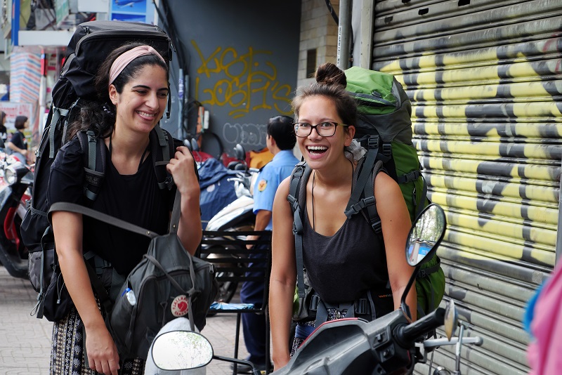 Two happy tourists in vacation by backpacking travel on Saigon street