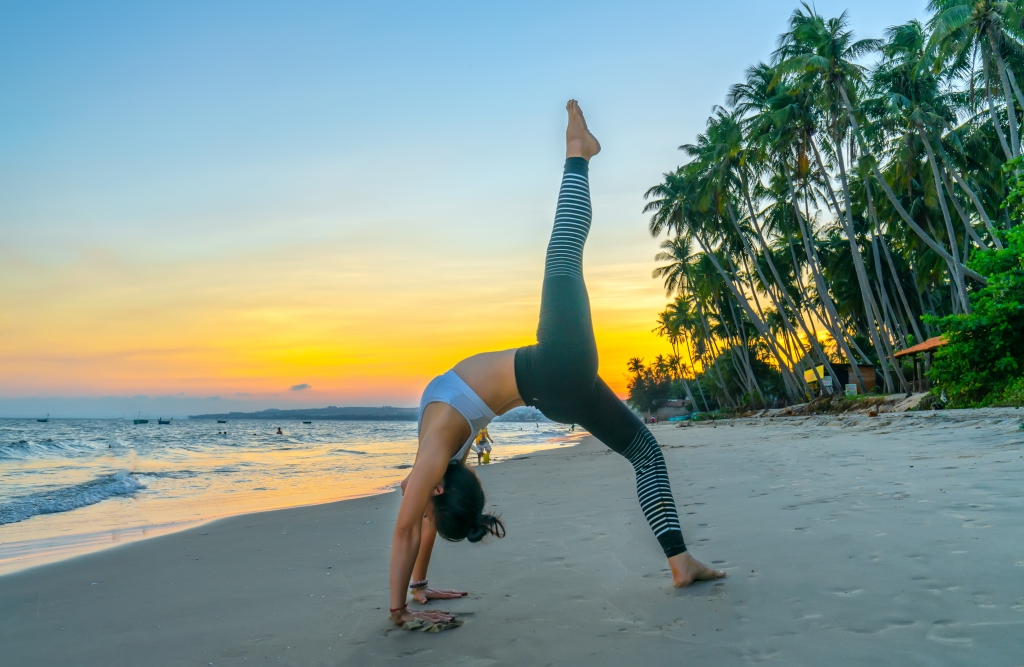 A tourist performing yoga exercises on the beach of Vietnam (Mui Ne Beach)