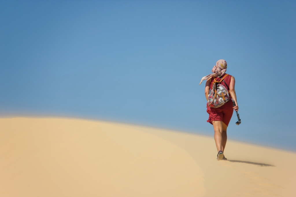 A tourist with backpack walking in the Sand Dunes of Mui Ne