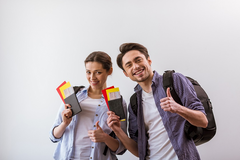 Attractive young couple in casual clothes and with backpacks holding passports and tickets ready to travel