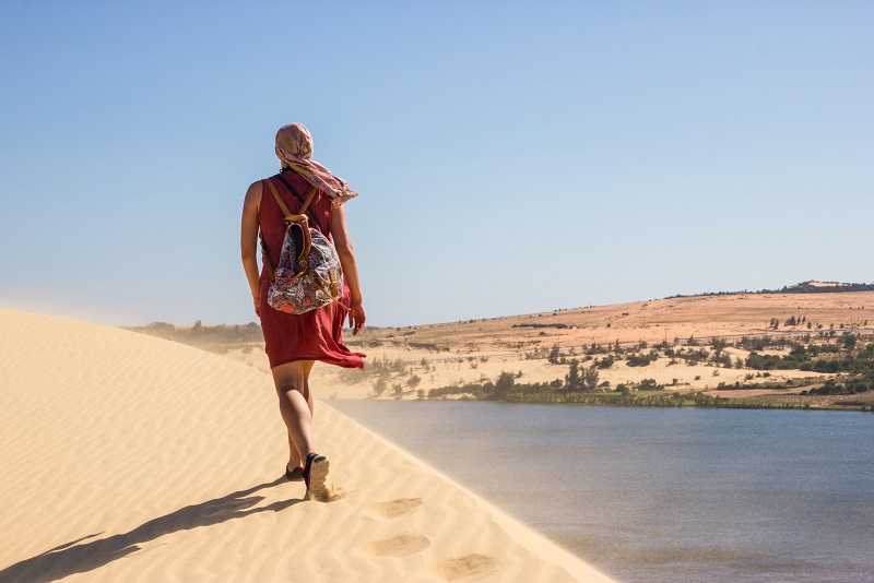 Back view of lonely person with backpack walking in desert of Mui Ne,Phan Thiet