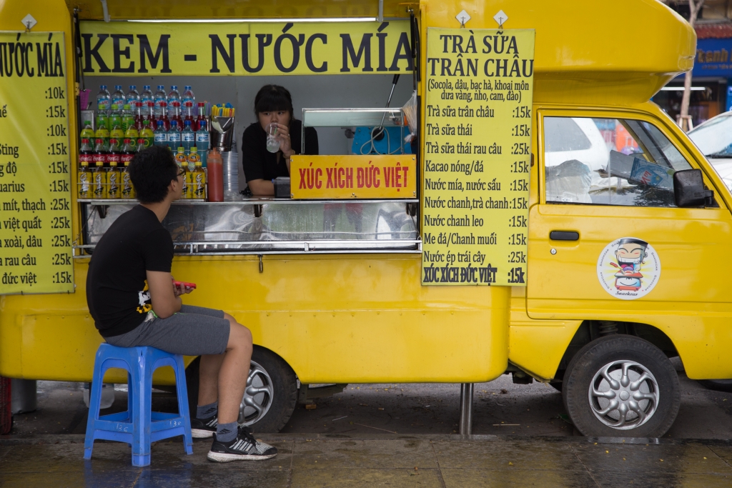 Vietnamese girl serving sugarcane and fresh tropical fruit juice on a street in Hanoi capital