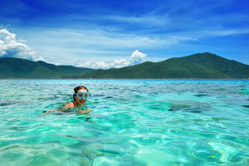 Happy girl with a mask floating in the azure tropical sea
