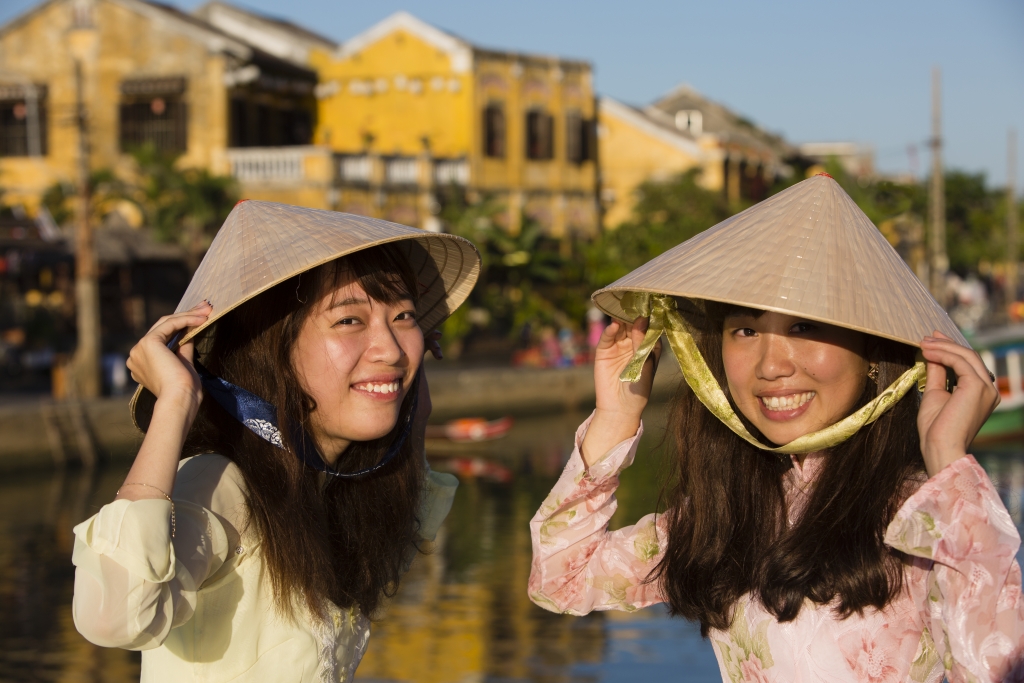 Tourists in aodai and with conical hats in Hoi An, Vietnam