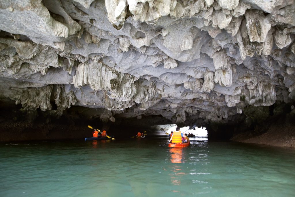Cayakers entering a sea cave in Ha Long bay